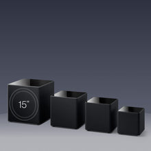 Set of four black KEF KUBE MIE Subwoofers with varying sizes on a gray background