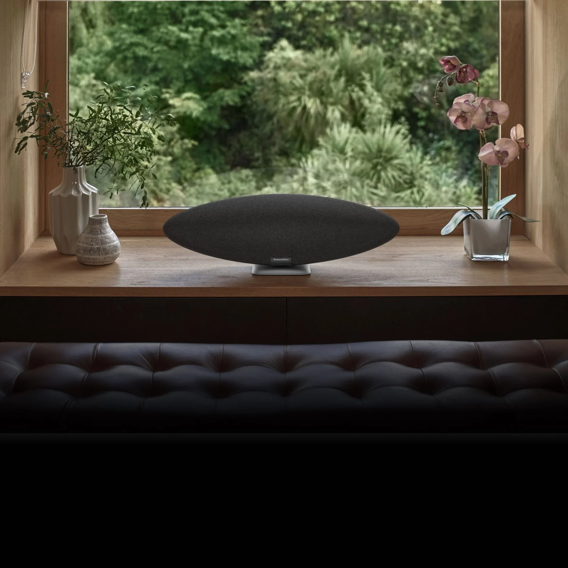 Bowers & Wilkins Zeppelin Pro Wireless Speaker in space grey on a windowsill in a modern living room.